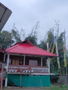帕西加特Tsering's Homestay Oyan的一间红色屋顶和旗帜的小房子