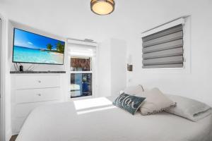 JewfishTiny Home on Waterfront, Bay Views, Deck, Pool的白色卧室设有1张带平面电视的床