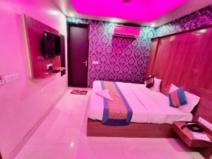 新德里hotel the paradise inn的粉红色的客房设有一张床和紫色的天花板
