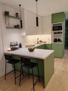 新格拉迪什卡Apartman „Karolina”的厨房配有绿色橱柜和带2把椅子的柜台。