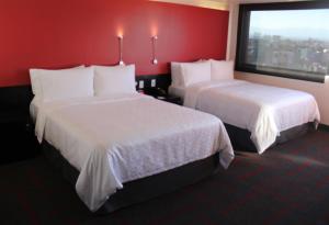 墨西哥城达利广场假日酒店的红色墙壁的酒店客房内的两张床
