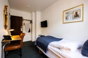 欧登塞Milling Hotel Windsor的酒店客房配有一张床、一张书桌和一台笔记本电脑