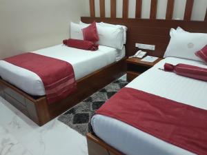 姆贝亚HOTEL MDOPE MBEYA的两张位于酒店客房的床,配有红色和白色床单
