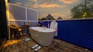 开罗Turquoise Pyramids & Grand Egyptian museum view Hotel的浴室配有白色浴缸和蓝色的墙壁