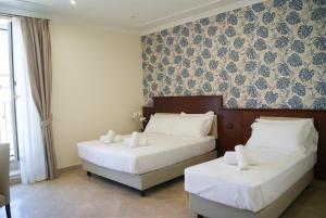 罗马Glam Luxury Rome的配有白色床单的酒店客房内的两张床