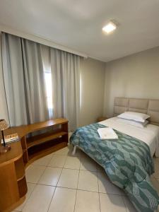 拉热斯Apartamento NOVO no centro/Via Gastronômica的一间卧室配有一张床、一张书桌和一个窗户。