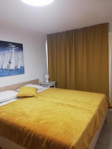 蒙达尼耶Apartments Tinjarosa的一间卧室配有一张带黄色床罩的大床