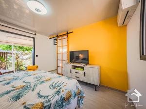 帕皮提Airport Pamatai Studio的一间卧室设有黄色的墙壁、一张床和一台电视机。