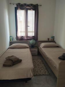 San SperateCasa Adele的配有窗户和地毯的客房内的两张床