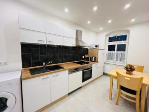 海德瑙Twenty Five Apartment的厨房配有白色橱柜和木桌