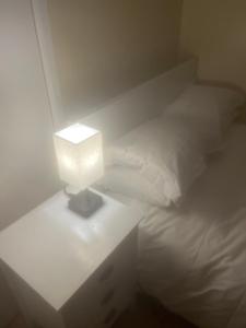 伦敦Chislet的一张带灯的白色床,放在床头柜上