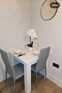 罗姆福特1-bed flat near Romford station的一张带椅子的白色桌子和花瓶