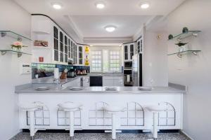 Humacao Villa - 8BR, Pool, Palmas, Ocean Views的厨房配有白色橱柜和带凳子的大柜台。