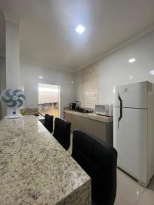 帕图斯迪米纳斯Apartamento Completo - Algarve 203 e 204的厨房配有大桌子、椅子和冰箱