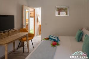 波拉波拉Matira Beach House的客厅配有桌子、电视和床。