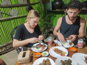 马德望Odambang Village Homestay的坐在餐桌旁吃食物的男人和女人