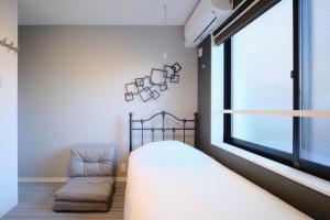 东京HJ PLACE TAKANAWA的卧室配有一张床和一把椅子,靠窗