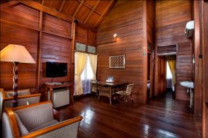 普卡Citra Cikopo Hotel & Family Cottages的客厅设有木墙、桌子和电视