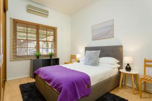 悉尼Spacious 3-Bed Mid Century Home Near CBD的一间卧室配有一张大床和紫色毯子