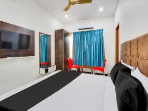 KhammamSuper OYO Hotel Arjun Residency的一间卧室配有一张床、一台电视和椅子