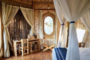 WaikeloMaringi Sumba by Sumba Hospitality Foundation的一间卧室配有一张床、一张书桌和一个窗户。