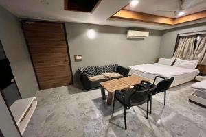 艾哈迈达巴德Hotel Om Balaji的配有床、桌子和沙发的房间