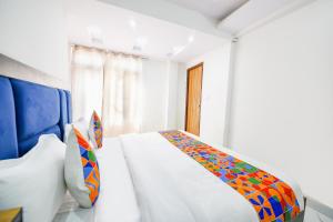 西姆拉FabHotel Beer Castle的白色卧室配有一张带彩色毯子的床