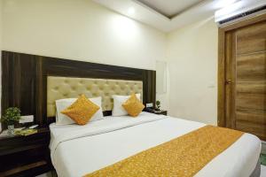 新德里Hotel IBY的卧室配有带橙色枕头的大型白色床