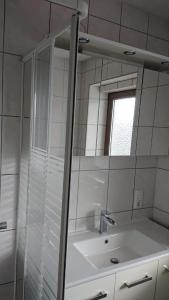 GönnernFerienwohnung Angelburg - Marburg Biedenkopf mit Balkon und Badewanne的白色的浴室设有水槽和镜子