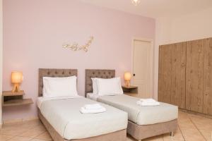 蒂锡利维Koukos Loft Apartments的一间卧室配有两张带白色床单和两盏灯的床。