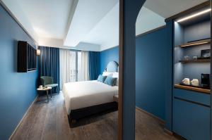 比雷埃夫斯Mitsis N'U Piraeus Port的一间卧室设有一张床和蓝色的墙壁