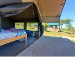 Sekenanikubwa mara safari lodge tent camp的一间卧室配有一张床和一个大型帐篷