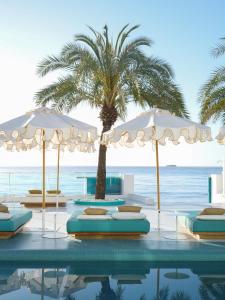 普拉亚登博萨Dorado Ibiza - Adults Only的一个带遮阳伞和棕榈树的游泳池