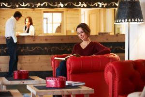 圣坎迪朵锡赛福特住宅酒店的坐在红椅上读书的女人