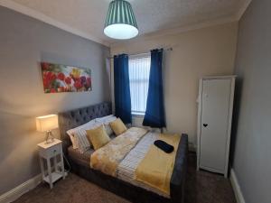 沃尔森德Executive 2-Bedroom House in Wallsend的一间卧室配有一张带蓝色窗帘的床和一扇窗户
