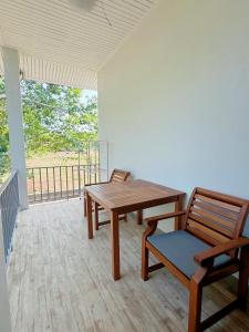 拉威海滩Rawai Valley Resort的带阳台的客房内的一张木桌和椅子