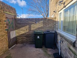 沃尔森德Executive 2-Bedroom House in Wallsend的两个垃圾桶坐在砖墙旁边