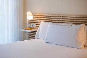 比利亚努埃瓦-赫尔特鲁MAREA ApartHotel的白色的床、白色枕头和灯
