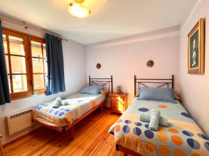 利亚沃尔西Rústic de Llavorsí的卧室设有两张床,铺有木地板,设有窗户。