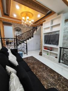 雅加达Rumah liburan 2 bedroom, 1 sofabed, 1 kitchen的客厅设有黑色沙发和楼梯。