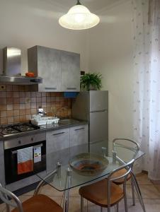 博洛尼亚Home Sweet Home的厨房配有玻璃桌、椅子和炉灶