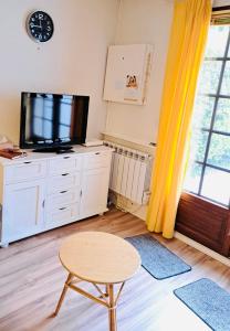 库尔瑟勒·苏尔·梅尔Maisonnette du bonheur的客厅配有电视、凳子和桌子