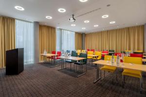 美因河畔法兰克福DoubleTree by Hilton Frankfurt Niederrad的一间会议室,配有桌子和五颜六色的椅子