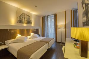 奥维多Gran Hotel España的酒店客房设有一张大床和一张书桌。