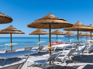 卡利亚里Palazzo Tirso MGallery Cagliari的海滩上的一组椅子和遮阳伞