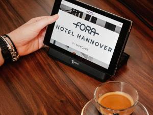 汉诺威Fora Hotel Hannover by Mercure的持着酒店挂靠网站的平板电脑的人