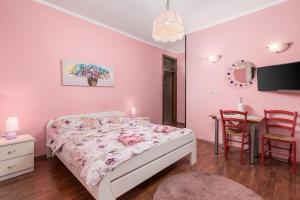 奥帕提亚Camelia & Martina apartments的一间卧室配有一张粉红色的墙壁和一张桌子。
