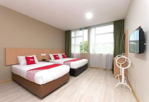 拉布安Capital O 89344 Labuan Avenue Hotel的酒店客房设有两张床和一台平面电视。