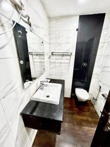 新德里Hotel Siam International的白色的浴室设有水槽和卫生间。