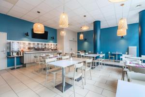 勒芒Appart'City Confort Le Mans Centre的餐厅拥有蓝色的墙壁和桌椅